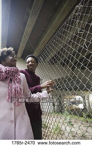 Young man holding a woman's hand on a fence View Large Photo Image Stock Image - Young man holding a woman's hand on a fence. Fotosearch