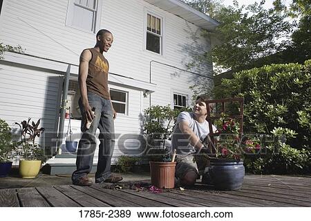 Young man moving plant to a new planter View Large Photo Image Stock Photo - Young man moving plant to a new planter. Fotosearch