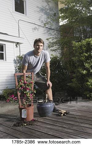 Young man moving plant to a new planter View Large Photo Image Stock Photograph - Young man moving plant to a new planter. Fotosearch