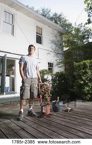 Young man moving plant to a new planter View Large Photo Image Stock Photography - Young man moving plant to a new planter. Fotosearch