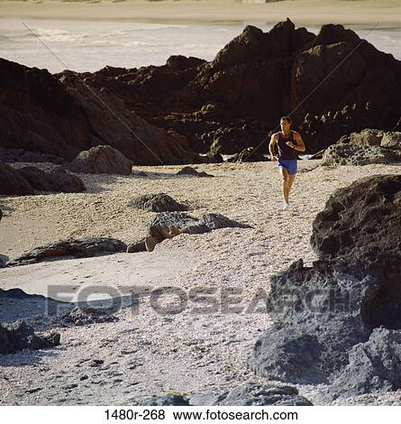 Stock Photo - Young man running on the beach. Fotosearch