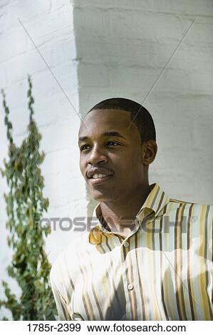 Young man standing outside a house View Large Photo Image Stock Photo - Young man standing outside a house. Fotosearch