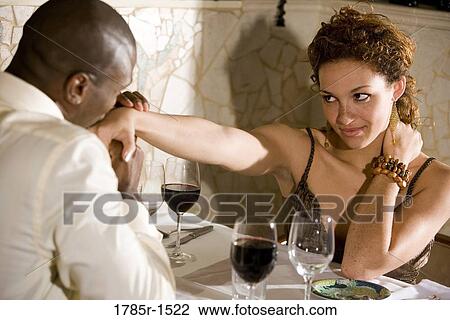 Stock Image - Young multi-ethnic romantic couple in restaurant. Fotosearch
