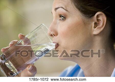 Stock Image - Young woman drinking a glass of water. Fotosearch