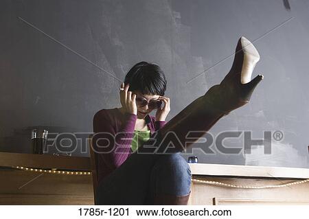 Young woman holding cigarette with leg raised View Large Photo Image Stock Image - Young woman holding cigarette with leg raised. Fotosearch