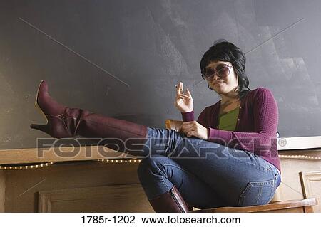 Young woman holding cigarette with leg raised View Large Photo Image Stock Image - Young woman holding cigarette with leg raised. Fotosearch