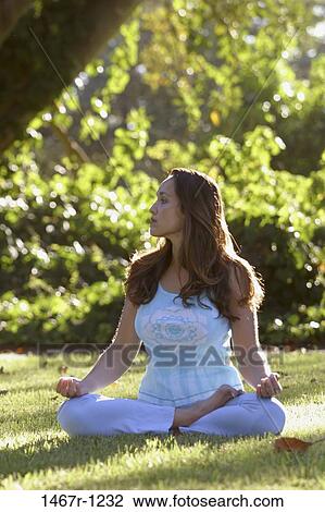 Young woman meditating on a lawn View Large Photo Image Stock Image - Young woman meditating on a lawn. Fotosearch