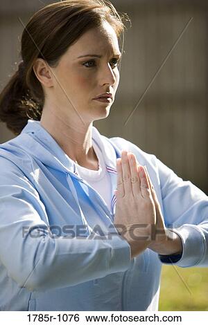Stock Photograph - Young woman meditating with hands joined. Fotosearch
