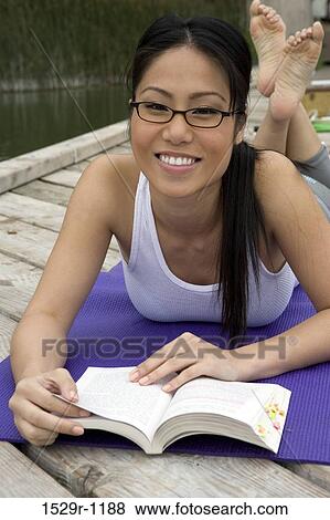 Young woman reading a book on a mat View Large Photo Image Stock Photo - Young woman reading a book on a mat. Fotosearch