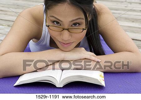 Stock Image - Young woman resting her head on a book. Fotosearch