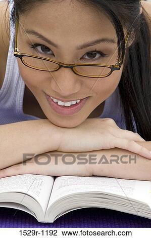 Stock Image - Young woman resting her head on a book. Fotosearch