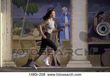 Young woman running on the sidewalk View Large Photo Image Stock Photo - Young woman running on the sidewalk. Fotosearch