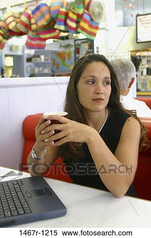 Young woman sitting alone in a restaurant holding a mug View Large Photo Image Stock Photography - Young woman sitting alone in a restaurant holding a mug. Fotosearch