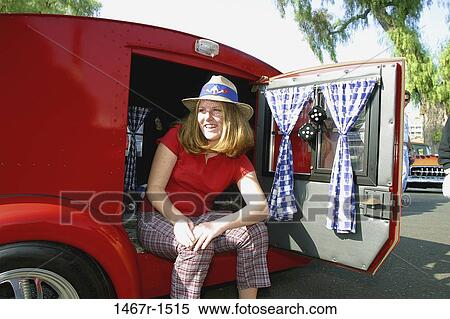 Stock Photography - Young woman sitting in a car with the door open. Fotosearch