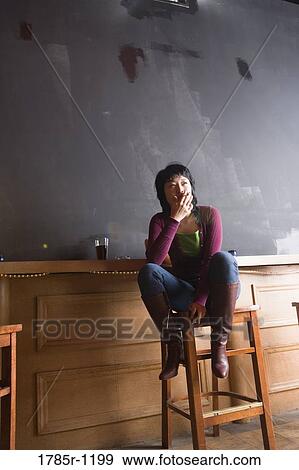 Young woman smoking cigarette at a a bar View Large Photo Image Stock Photo - Young woman smoking cigarette at a a bar. Fotosearch