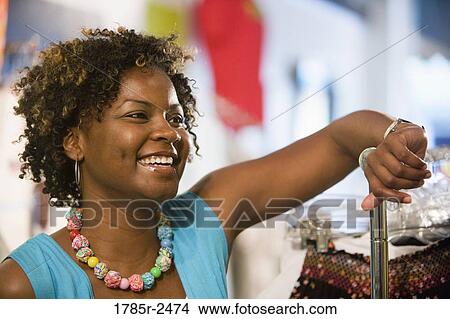 Picture - Young woman standing in a boutique. Fotosearch