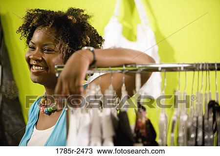 Stock Image - Young woman standing in a boutique. Fotosearch