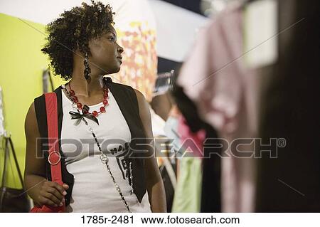 Young woman standing in a boutique View Large Photo Image Stock Image - Young woman standing in a boutique. Fotosearch