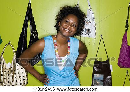 Young woman standing in a boutique View Large Photo Image Stock Photograph - Young woman standing in a boutique. Fotosearch