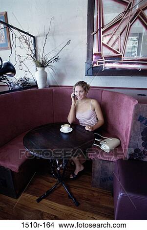 Young woman talking on a mobile phone at a restaurant View Large Photo Image Picture - Young woman talking on a mobile phone at a restaurant. Fotosearch