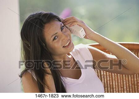 Young woman talking on a telephone smiling View Large Photo Image Stock Image - Young woman talking on a telephone smiling. Fotosearch