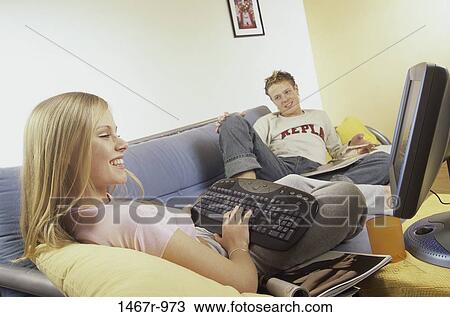 Young woman working on a computer with a young man sitting beside her View Large Photo Image Stock Image - Young woman working on a computer with a young man sitting beside her. Fotosearch