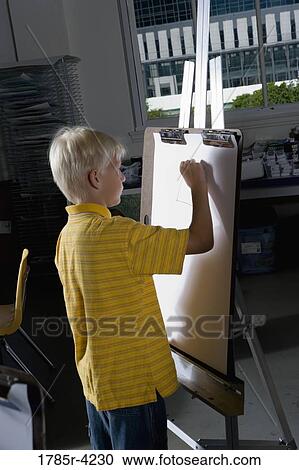 A boy drawing on an easel in art class View Large Photo Image Stock Image - A boy drawing on an easel in art class. Fotosearch