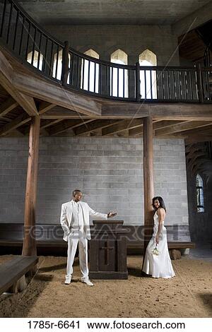 Stock Image - A bride and a groom next to an altar inside a medieval castle. Fotosearch