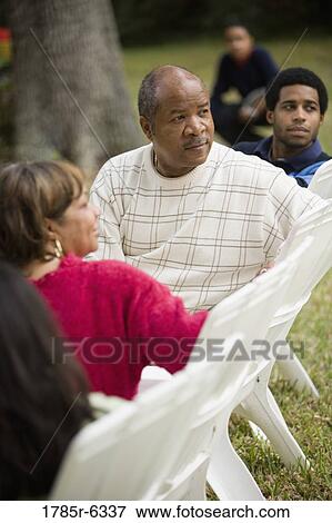 A family sitting on lawn chairs looking behind them View Large Photo Image Stock Photo - A family sitting on lawn chairs looking behind them. Fotosearch