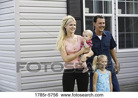 A family standing together outside their home View Large Photo Image Stock Photograph - A family standing together outside their home. Fotosearch