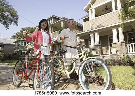 A mature couple walking with bicycles in neighborhood of two-storey houses View Large Photo Image Stock Image - A mature couple walking with bicycles in neighborhood of two-storey houses. Fotosearch