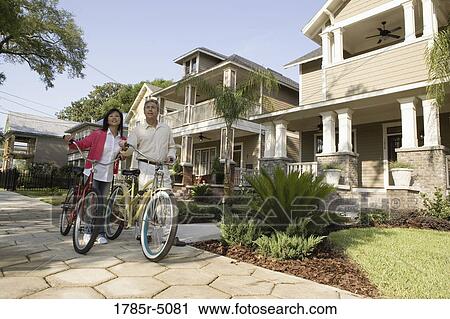 A mature couple walking with bicycles in neighborhood of two-storey houses View Large Photo Image Stock Image - A mature couple walking with bicycles in neighborhood of two-storey houses. Fotosearch