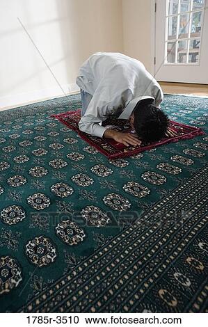 Stock Image - A Muslim man bowing head on a prayer mat. Fotosearch