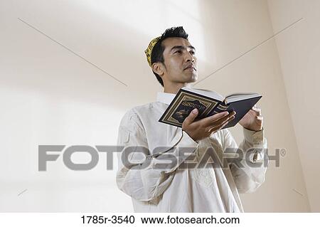 Stock Image - A Muslim man holding Koran. Fotosearch