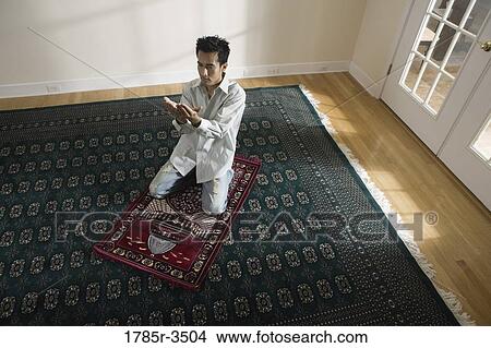 A Muslim man praying on a prayer mat View Large Photo Image Picture - A Muslim man praying on a prayer mat. Fotosearch