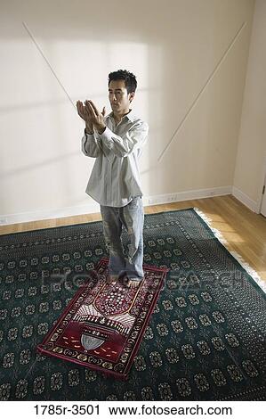 Stock Image - A Muslim man praying on a prayer mat. Fotosearch