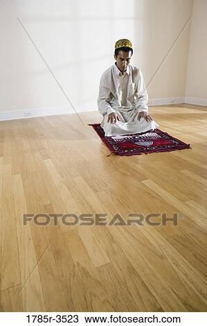Stock Image - A Muslim man praying on a prayer mat. Fotosearch
