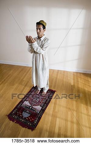 Stock Photo - A Muslim man praying on a prayer mat. Fotosearch