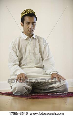 Stock Photograph - A Muslim man praying on a prayer mat. Fotosearch