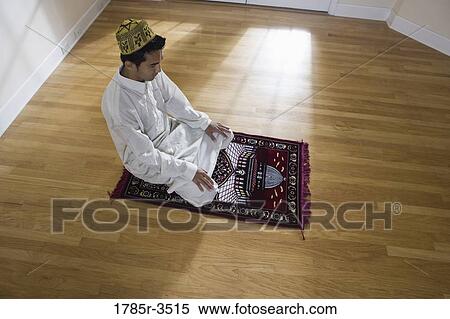 Stock Photography - A Muslim man praying on a prayer mat. Fotosearch