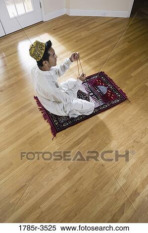 Stock Photography - A Muslim man praying on a prayer mat. Fotosearch