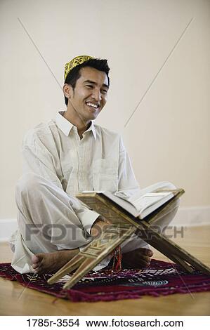 A Muslim man reading Koran on a prayer mat View Large Photo Image Picture - A Muslim man reading Koran on a prayer mat. Fotosearch