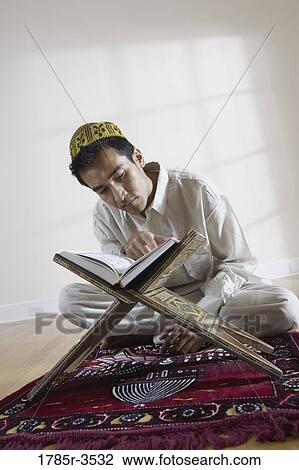 A Muslim man reading Koran on a prayer mat View Large Photo Image Stock Image - A Muslim man reading Koran on a prayer mat. Fotosearch