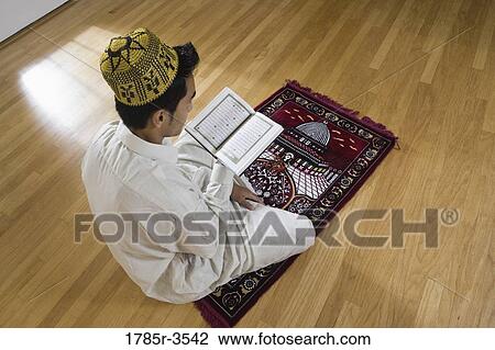 A Muslim man reading Koran on a prayer mat View Large Photo Image Stock Image - A Muslim man reading Koran on a prayer mat. Fotosearch