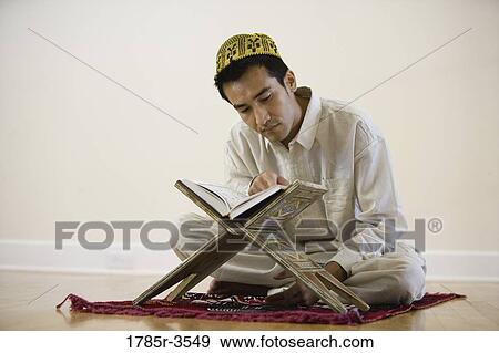 A Muslim man reading Koran on a prayer mat View Large Photo Image Stock Photo - A Muslim man reading Koran on a prayer mat. Fotosearch