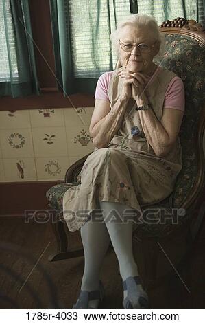 A smiling senior woman sitting on a chair View Large Photo Image Stock Image - A smiling senior woman sitting on a chair. Fotosearch