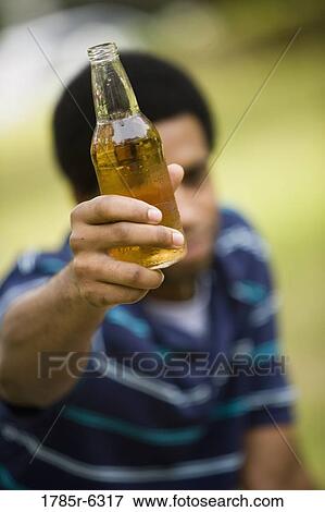 A young man holding up a drink bottle View Large Photo Image Stock Photo - A young man holding up a drink bottle. Fotosearch