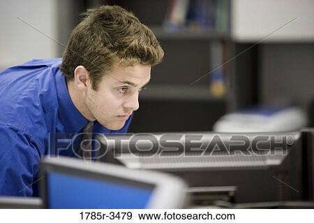 A young man looking at the computer monitor View Large Photo Image Stock Photo - A young man looking at the computer monitor. Fotosearch