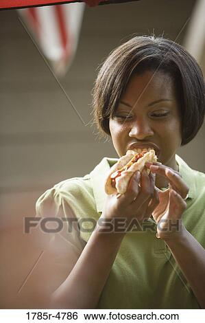 A young woman eating hotdog View Large Photo Image Stock Photograph - A young woman eating hotdog. Fotosearch