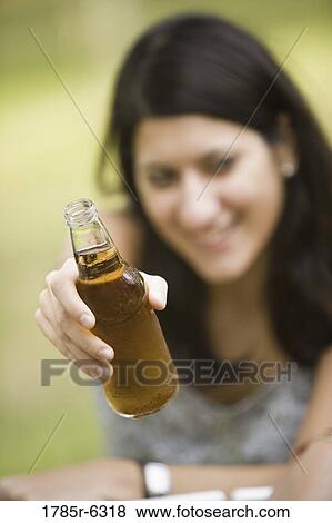 A young woman holding up a drink bottle View Large Photo Image Stock Photo - A young woman holding up a drink bottle. Fotosearch